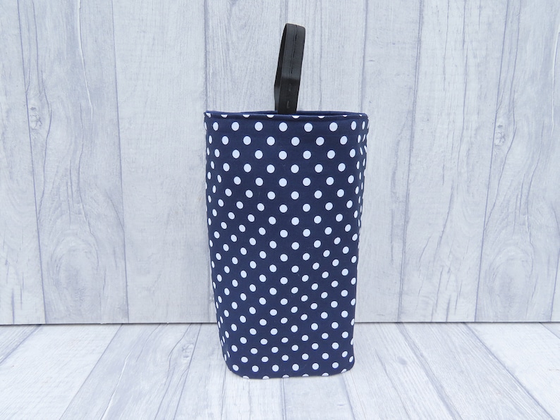 Puede incluir: Un contenedor de almacenamiento de tela azul y blanco con lunares y un asa negra.