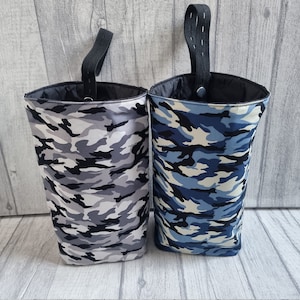 Puede incluir: Dos contenedores de almacenamiento de tela colgantes con patrones de camuflaje. Un contenedor es gris y negro, el otro es azul y blanco.