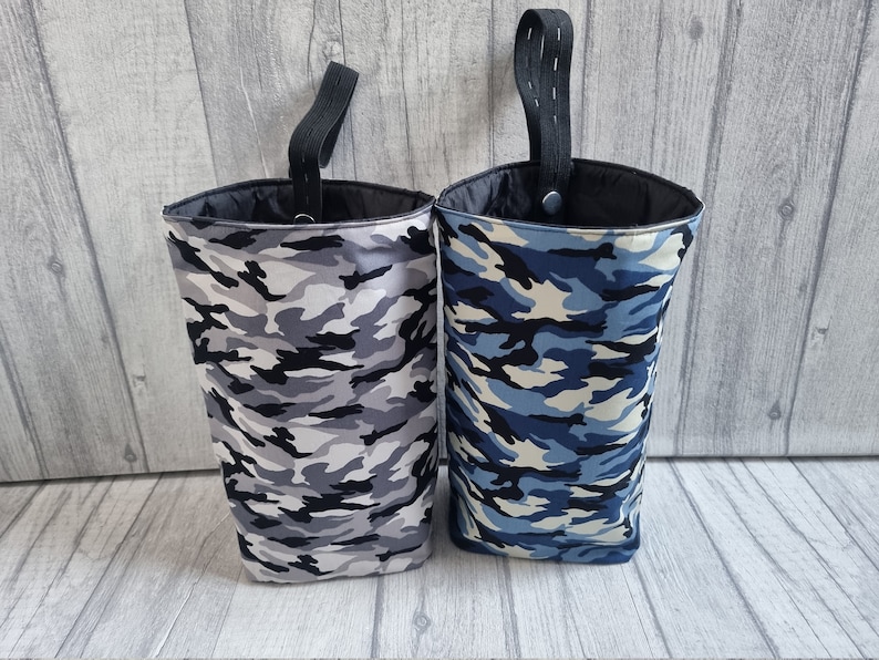 Puede incluir: Dos contenedores de almacenamiento de tela colgantes con patrones de camuflaje. Un contenedor es gris y negro, el otro es azul y blanco.