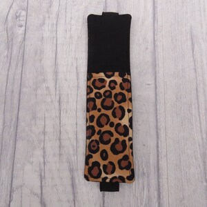 May include: A black and brown leopard print fabric phone case with a black flap.