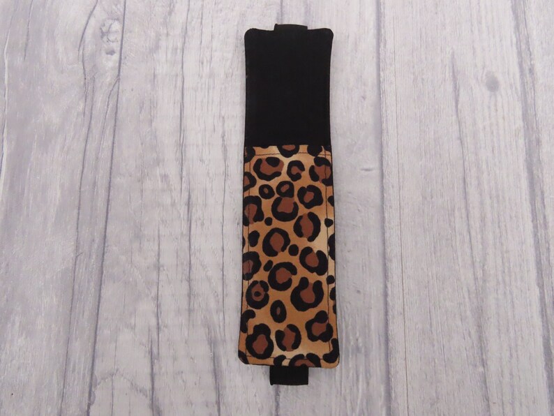 May include: A black and brown leopard print fabric phone case with a black flap.