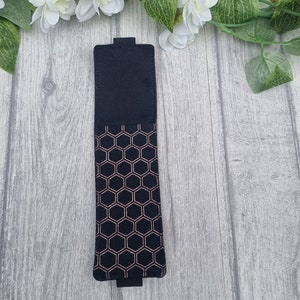 May include: A black felt bookmark with a rose gold honeycomb pattern.