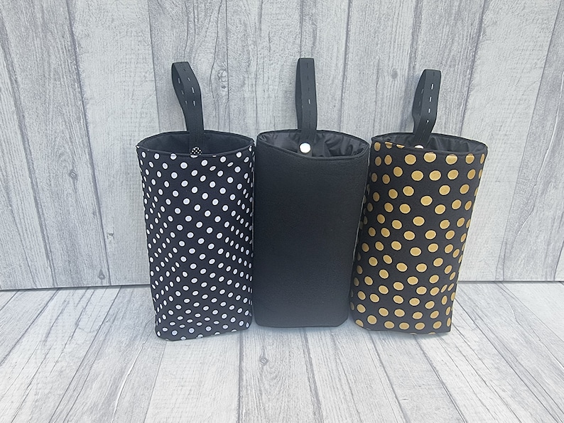 Puede incluir: Tres bolsas de almacenamiento de tela colgantes con tela negra y diferentes patrones. La bolsa de la izquierda tiene lunares blancos, la bolsa del medio es negra s&oacute;lida y la bolsa de la derecha tiene lunares dorados.