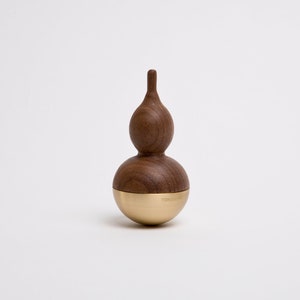 May include: A wooden spinning top with a brown gourd shape and a gold metal base. The top is made of walnut wood and has a smooth, polished finish.