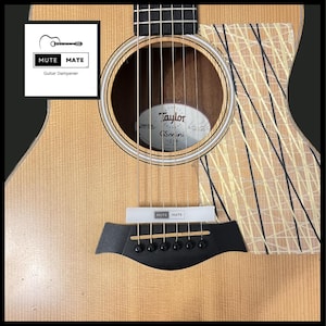 May include: Close-up of a Taylor GS Mini acoustic guitar with a black and white striped design on the body. The guitar has a natural wood finish and a black bridge.