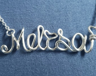 May include: Silver necklace with the name "Melissa" spelled out in wire.