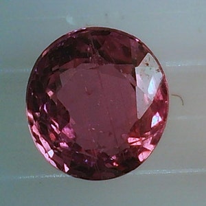 Könnte beinhalten: Zwei runde, rosafarbene Edelsteine mit facettierten Kanten. Die Edelsteine liegen auf einem weißen Hintergrund.