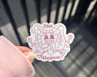 May include: A white sticker with a cartoon illustration of intestines in a smiling face design. The sticker has the words "Shit Happens!" in red lettering.
