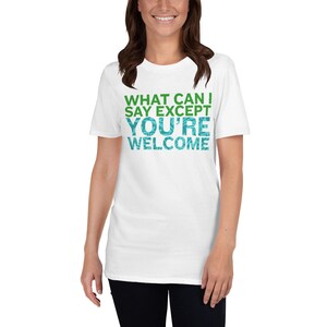 Puede incluir: Camiseta blanca con texto verde y azul que dice "What can I say except you're welcome".