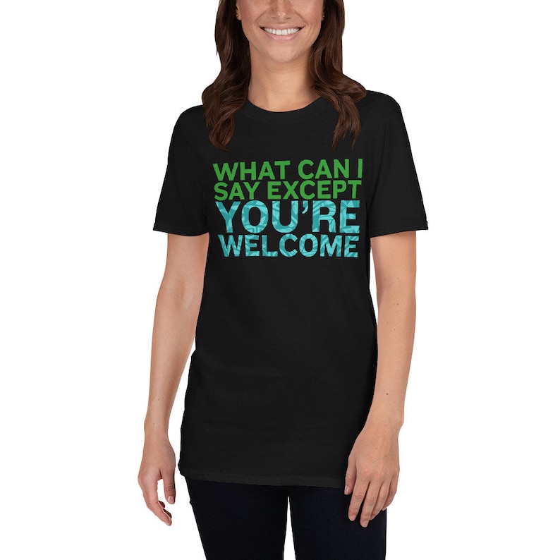 Puede incluir: Camiseta negra con texto verde y azul que dice "What can I say except you're welcome."
