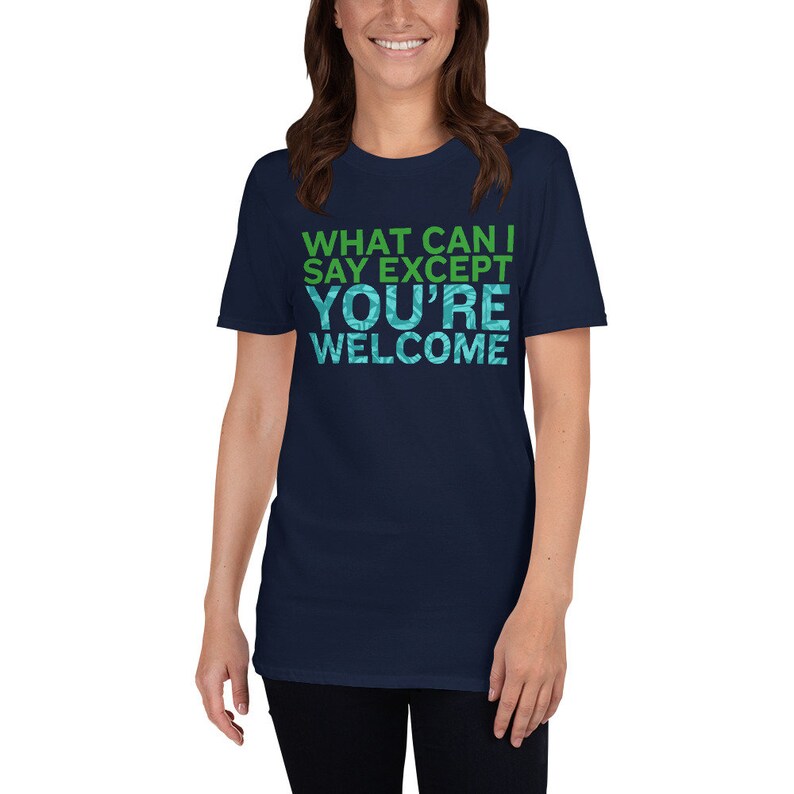 Puede incluir: Una camiseta azul marino con un estampado gr&aacute;fico verde y azul que dice "What can I say except you're welcome".