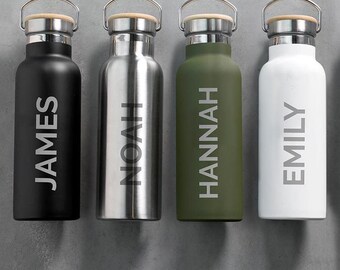 Puede incluir: Cuatro botellas de agua de acero inoxidable con nombres personalizados: James, Noah, Hannah y Emily. Las botellas son negras, plateadas, verdes y blancas.