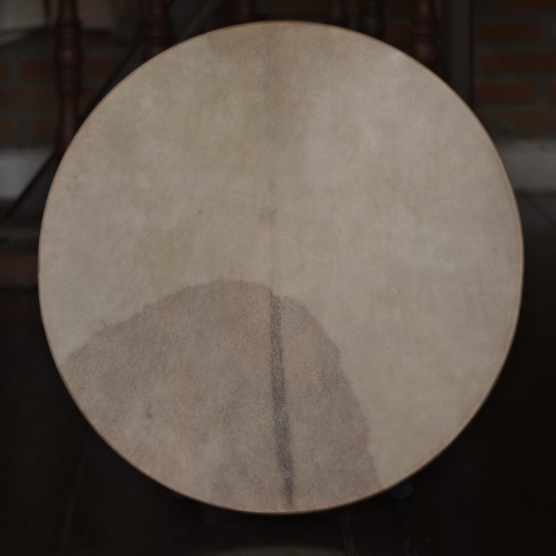 May include: A round, light brown drum head with a darker brown patch in the center.