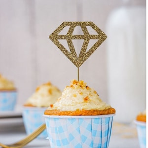 May include: Gold glitter diamond cupcake topper on a blue and white cupcake. The text "Farben personalisierbar" is visible in the background.
