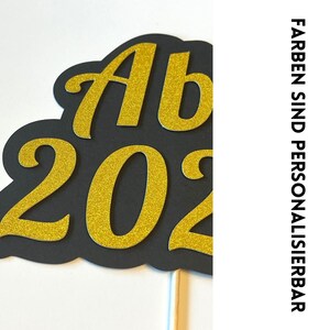 May include: Black and gold glitter 'Ab 202' sign on a stick. The sign is perfect for a graduation party or celebration.