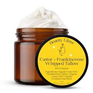 May include: A brown glass jar filled with white whipped tallow. The jar has a black and yellow label that reads "Beauty Glow Castor + Frankincense Whipped Tallow 100% Organic" and lists ingredients. The jar contains 2 oz.