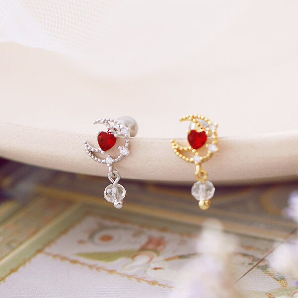 Blood red heart gemstone in the centre of a bobbly textured crescent moon, with clear colourless gem pendent. Sold individually,