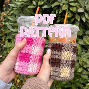 May include: Two clear plastic cups with orange straws are held in hands, each wrapped in a crocheted cozy. One cozy is pink and white, the other is brown, tan, and brown. The text "PDF PATTERN" is superimposed on the image.