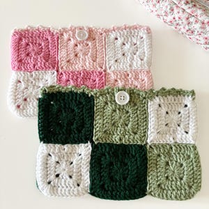 Könnte beinhalten: Zwei gehäkelte Beutel mit verschiedenen Farbkombinationen. Der obere Beutel ist rosa, weiß und hellrosa. Der untere Beutel ist grün, weiß und hellgrün. Beide Beutel haben einen weißen Knopf.