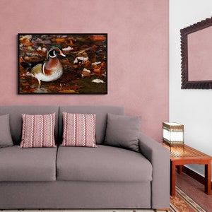 May include: A gray sofa with two throw pillows, a wooden end table with a lamp, and a framed picture of a wood duck on a pink wall.