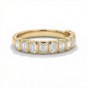 Peut inclure: Une bague en or ornée d'une série de pierres précieuses rectangulaires et transparentes. Les pierres sont serties dans des chatons individuels, créant une ligne continue autour de la bague. La bague a une finition polie et brillante.