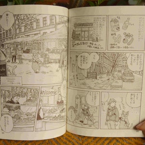 Puede incluir: Una p&aacute;gina de manga en blanco y negro con ilustraciones de personas y animales en un entorno urbano. El texto del manga est&aacute; en japon&eacute;s. El manga est&aacute; abierto a una p&aacute;gina con el texto "BIO!" y "sebr&uuml;he".