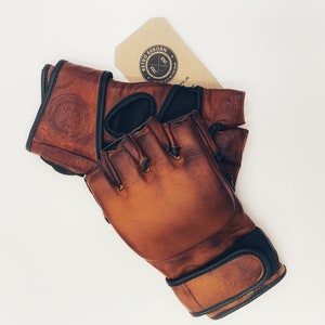 May include: Brown leather boxing gloves with black accents and a logo that says "Retro Reborn" on the wrist strap.