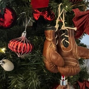 May include: A Christmas tree decorated with red and white baubles, including a pair of brown leather boxing gloves.
