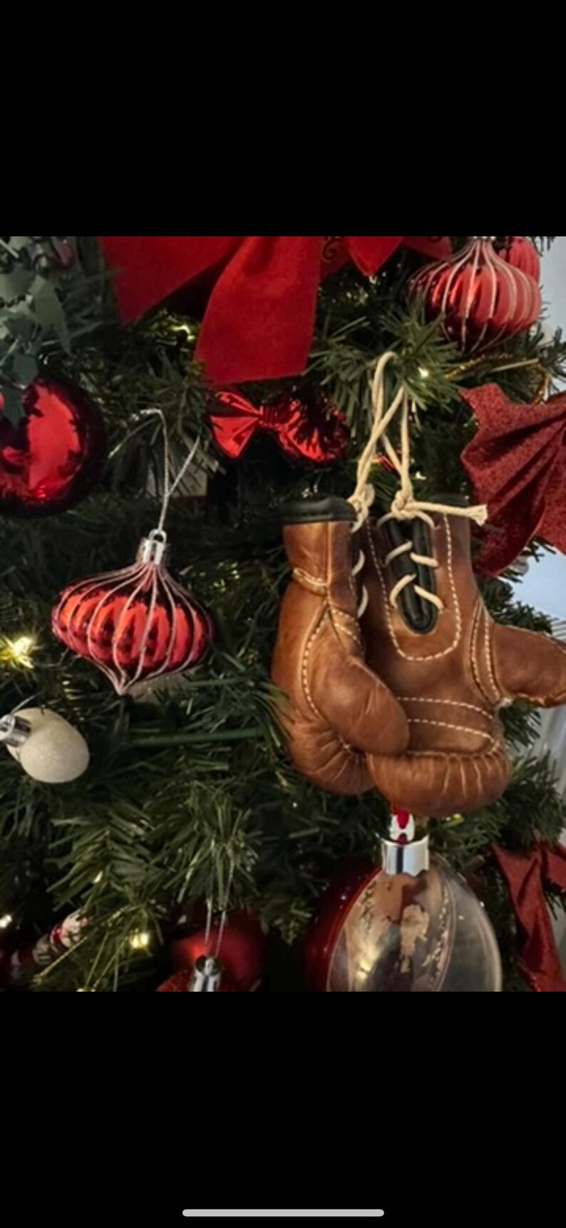 May include: A Christmas tree decorated with red and white baubles, including a pair of brown leather boxing gloves.