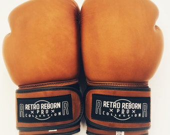 May include: Pair of brown leather boxing gloves with black trim and the text "Retro Reborn x Prox Collection" on the wrist straps.