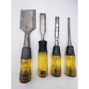 May include: Four vintage wood chisels with metal blades and yellow plastic handles. The chisels vary in size, with the largest having a wide blade. The handles have black accents and are marked with the Stanley brand.