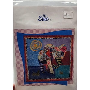 May include: A fabric art kit with an elephant design. The elephant is made of various patterned fabrics in shades of red, blue, and purple. The background includes a sun and a checkered border. The package is labeled "Ellie."
