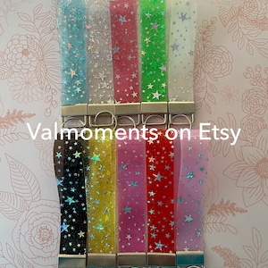 May include: Ten clear keychain straps with silver key rings. Each strap has a different color background with white stars. The colors are light blue, white, pink, green, white, black, yellow, pink, red, and light pink.