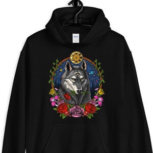 K&ouml;nnte beinhalten: Schwarzer Kapuzenpullover mit einem grafischen Aufdruck eines Wolfes mit drei Augen, umgeben von Blumen und einem himmlischen Hintergrund.