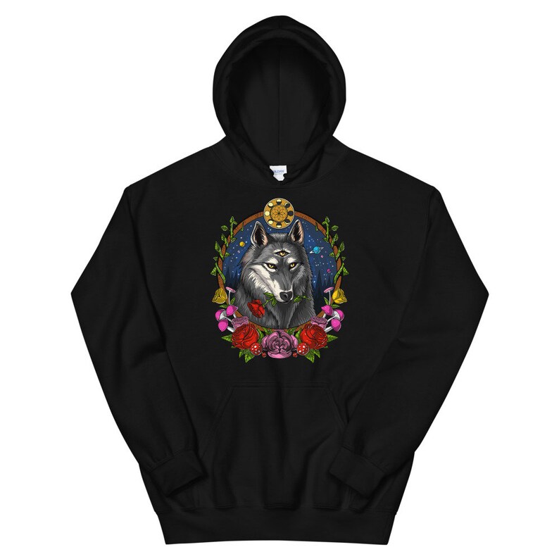 K&ouml;nnte beinhalten: Schwarzer Kapuzenpullover mit einem grafischen Aufdruck eines Wolfes mit drei Augen, umgeben von Blumen und Pilzen. Der Wolf h&auml;lt eine rote Rose im Maul. Der Hintergrund ist dunkelblau mit Sternen und Planeten.