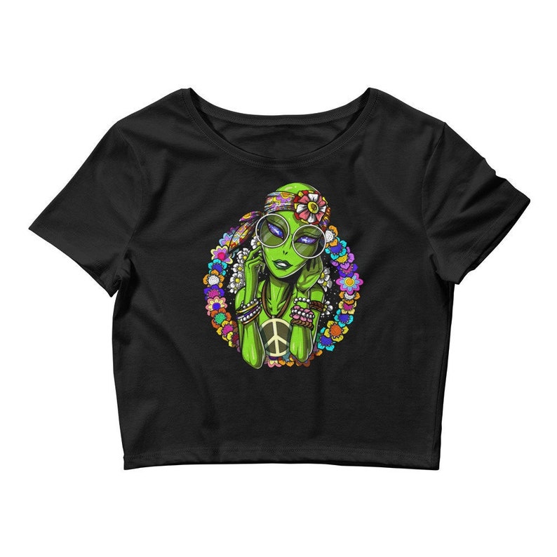 May include: A black cropped t-shirt featuring a graphic of a green alien woman wearing a flower crown and peace sign necklace. The alien has purple eyeshadow and is wearing round sunglasses.