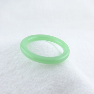 Puede incluir: Un anillo simple de jade verde. El anillo es liso y pulido.
