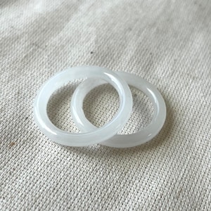 May include: Two white jade rings stacked on top of each other. The rings are smooth and polished.