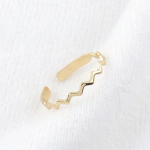 May include: A gold-colored ring with a zig-zag pattern.