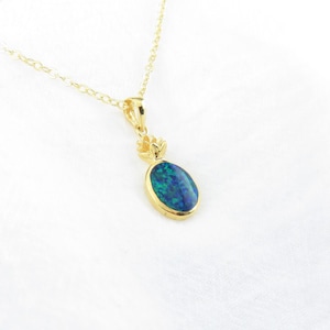 Op de afbeelding: Een gouden ketting met een hanger met een blauwe ovale opaal-steen in een gouden kroon.