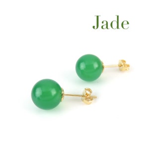 May include: A pair of jade green stud earrings with gold posts. The earrings are round and have a smooth, polished finish.  Jade.