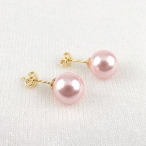 May include: A pair of gold stud earrings with pink pearl accents.