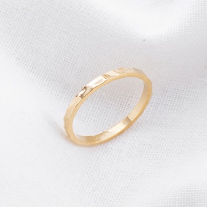 May include: A thin gold band ring with a hammered texture.