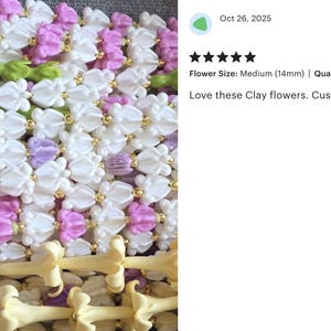 May include: Close-up of a collection of clay flowers in white, pink, purple, and green. The flowers are strung together with gold-colored beads. The text in the image says "Love these Clay flowers. Customers love the color too."
