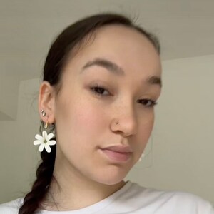 May include: White daisy flower earrings with gold-colored hoops. The earrings are a simple, elegant design, perfect for everyday wear. The earrings are lightweight and add a touch of nature-inspired charm.