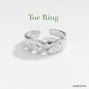 Può includere: Anello per dita dei piedi in argento con un design floreale. L'anello è regolabile e ha una finitura lucida.