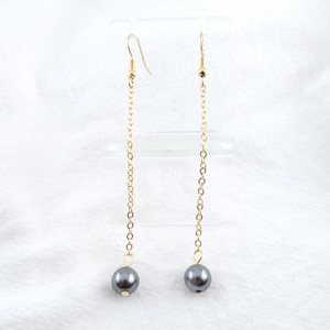 May include: A pair of long, gold chain earrings with a single dark gray pearl at the end of each chain.
