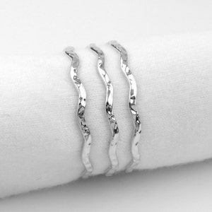 May include: Three silver rings with a wavy, textured design.