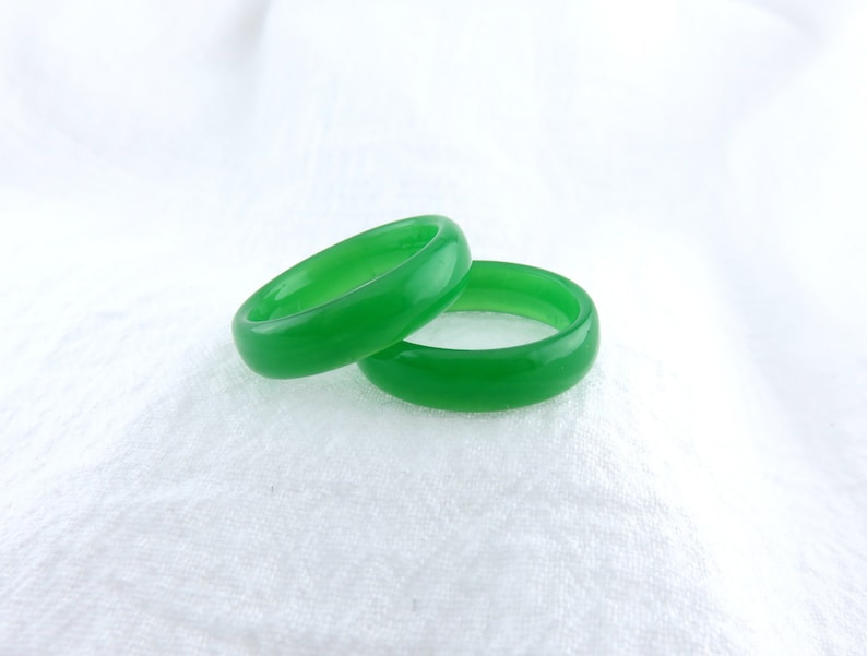 May include: Two green jade rings stacked on top of each other. The rings are smooth and polished.