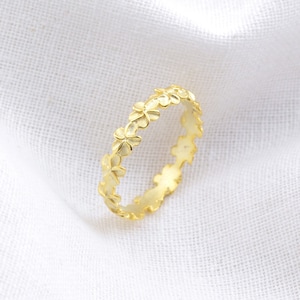 Può includere: Un anello d'oro con un delicato design floreale. L'anello è realizzato in metallo liscio e ha uno stile semplice ed elegante.